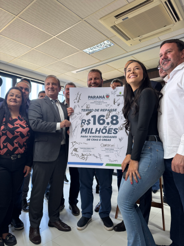 Rogério Carboni e lideranças posam diante da projeção arquitetônica de um CRAS.